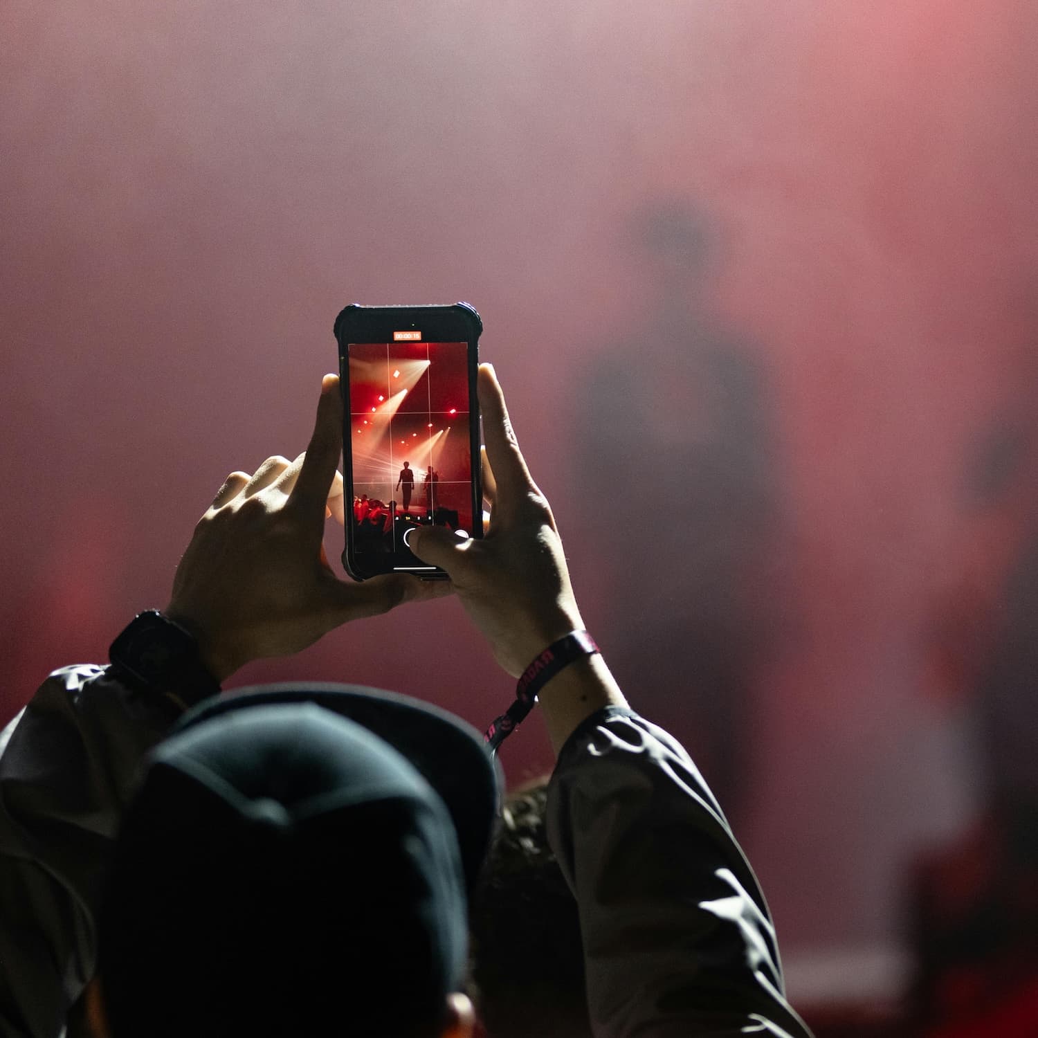 Man mit Cappie macht ein Foto mit dem Smartphone von einem Event